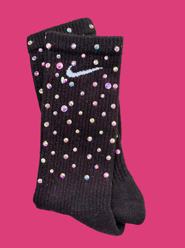 A pair of black Nike crew socks embellished with iridescent rhinestones and a white embroidered Nike swoosh